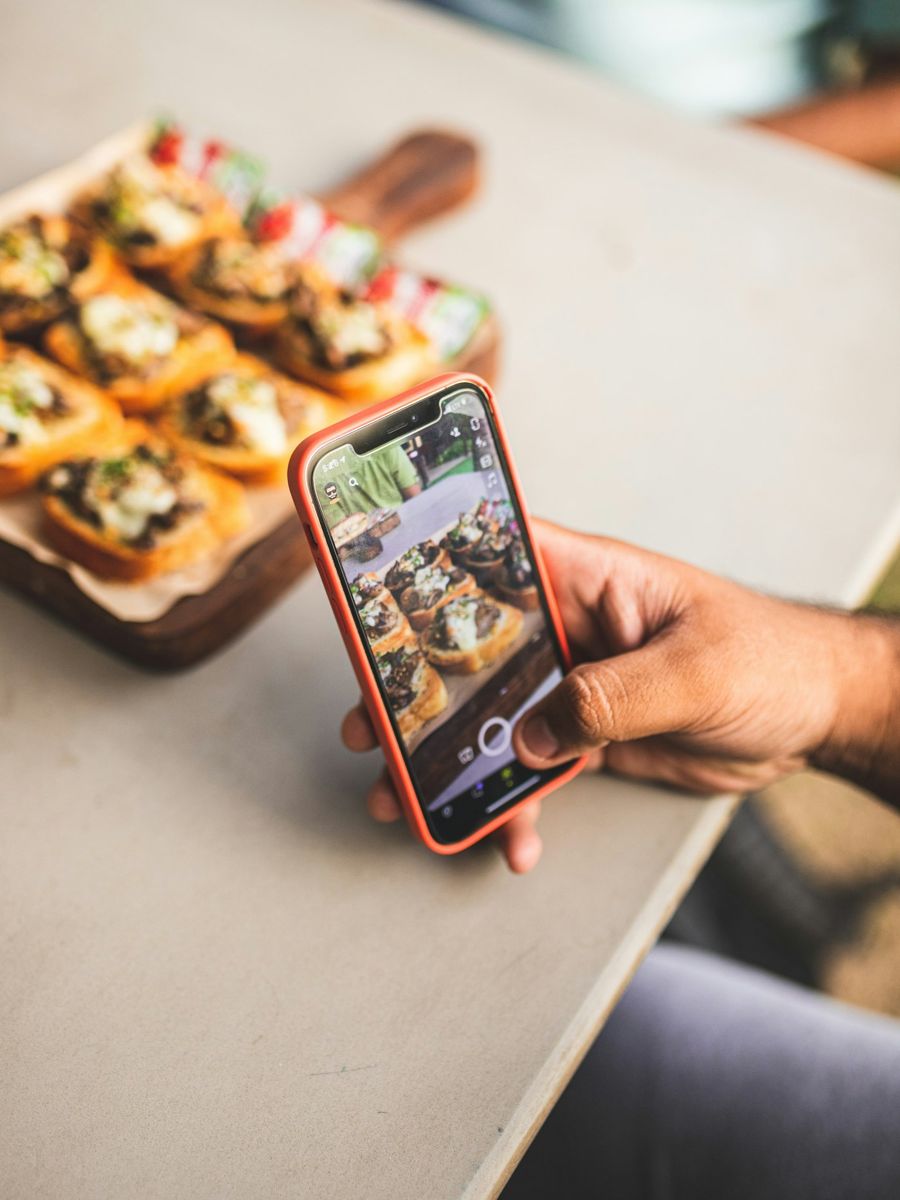 A person filming food with a smartphone in a café
